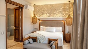 A modern bedroom with a large bed, a wooden bench, and two wall-mounted lamps. - Casa Sonara (Cartagena)