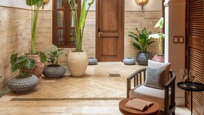 A spacious indoor area with a tiled floor, a wooden door, and a seating area with a table and chairs. - Casa Sonara (Cartagena)