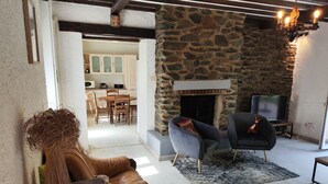 Un salon chaleureux avec une cheminée en pierre, un téléviseur et un coin salon confortable.