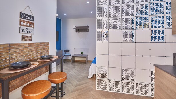 Une cuisine moderne avec un mur recouvert de briques, un coin repas avec des tabourets et un mur décoratif orné de panneaux suspendus.