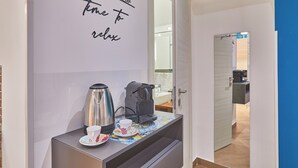 Une petite cuisine équipée d’une machine à café, d’une tasse et d’une bouilloire, le tout disposé sur un plateau.