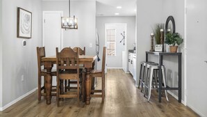 A dining area with a wooden table and chairs, a hanging light fixture, and a small bar area with stools and a mirror. - Tranquil Getaway For 8 (Branson)