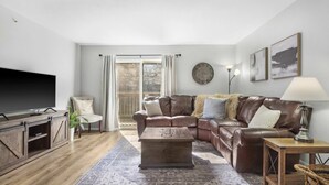 A living room with a leather sofa, a coffee table, a TV, and a lamp. - Tranquil Getaway For 8 (Branson)