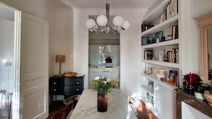 Une cuisine moderne dotée d’un plan de travail en marbre, d’un lustre et d’un coin repas avec des chaises et une table.