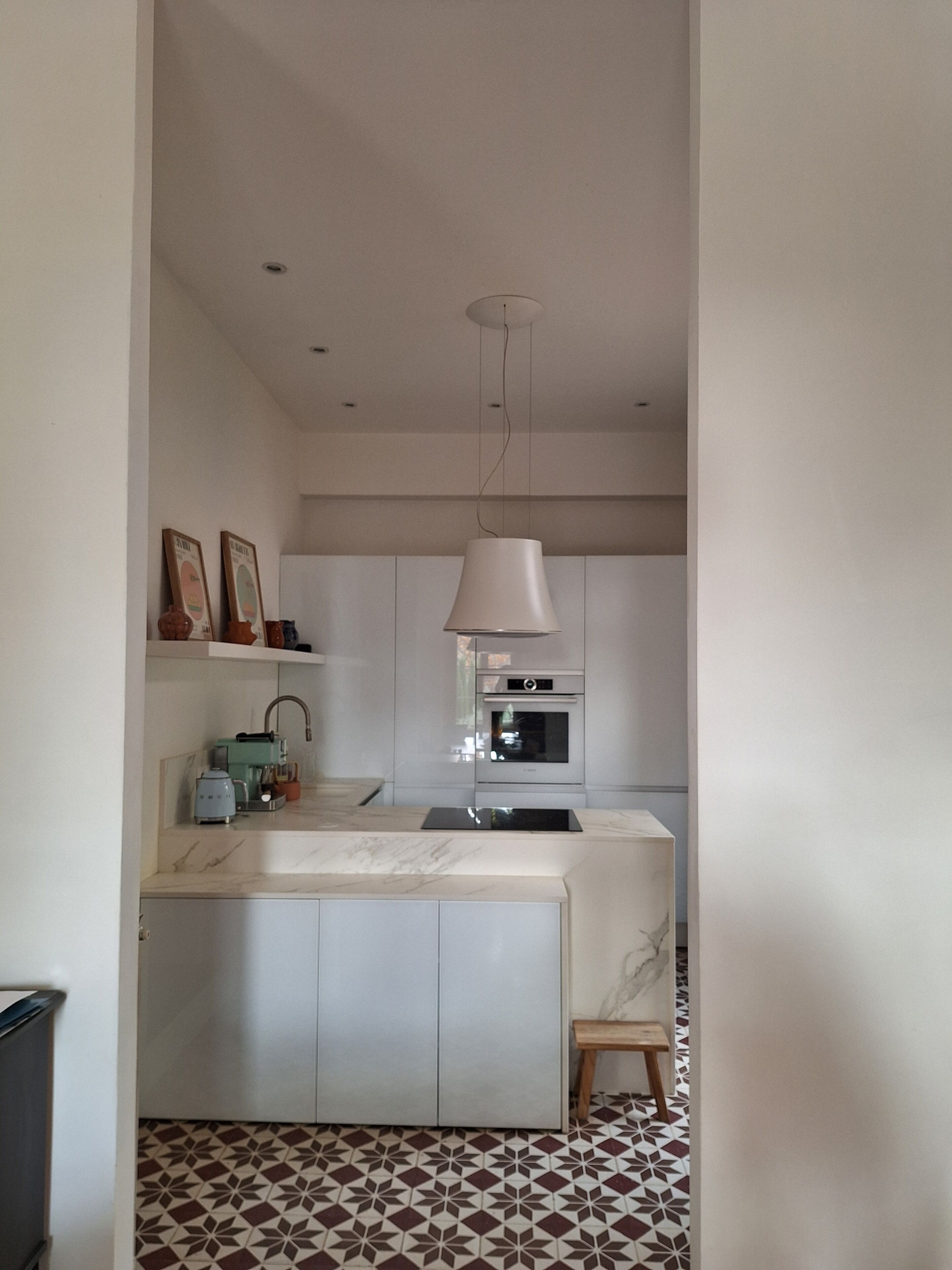 Una cucina moderna con un piano di lavoro in marmo, forno integrato e lampada a sospensione.