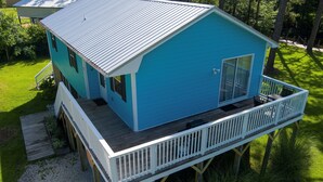 Een huis met twee verdiepingen, met een blauwe gevel, een houten terras en een witte balustrade.