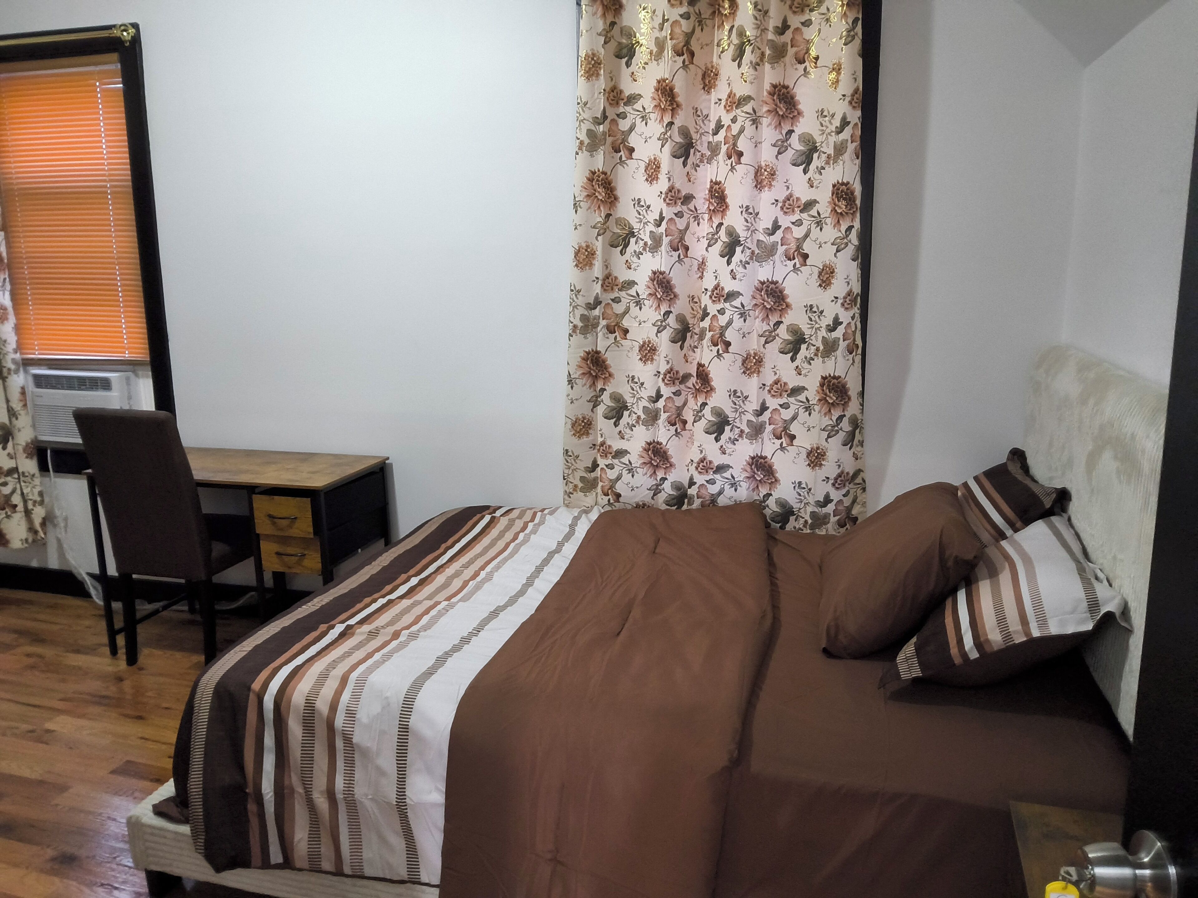 A bedroom with a bed, a desk, and a chair.
