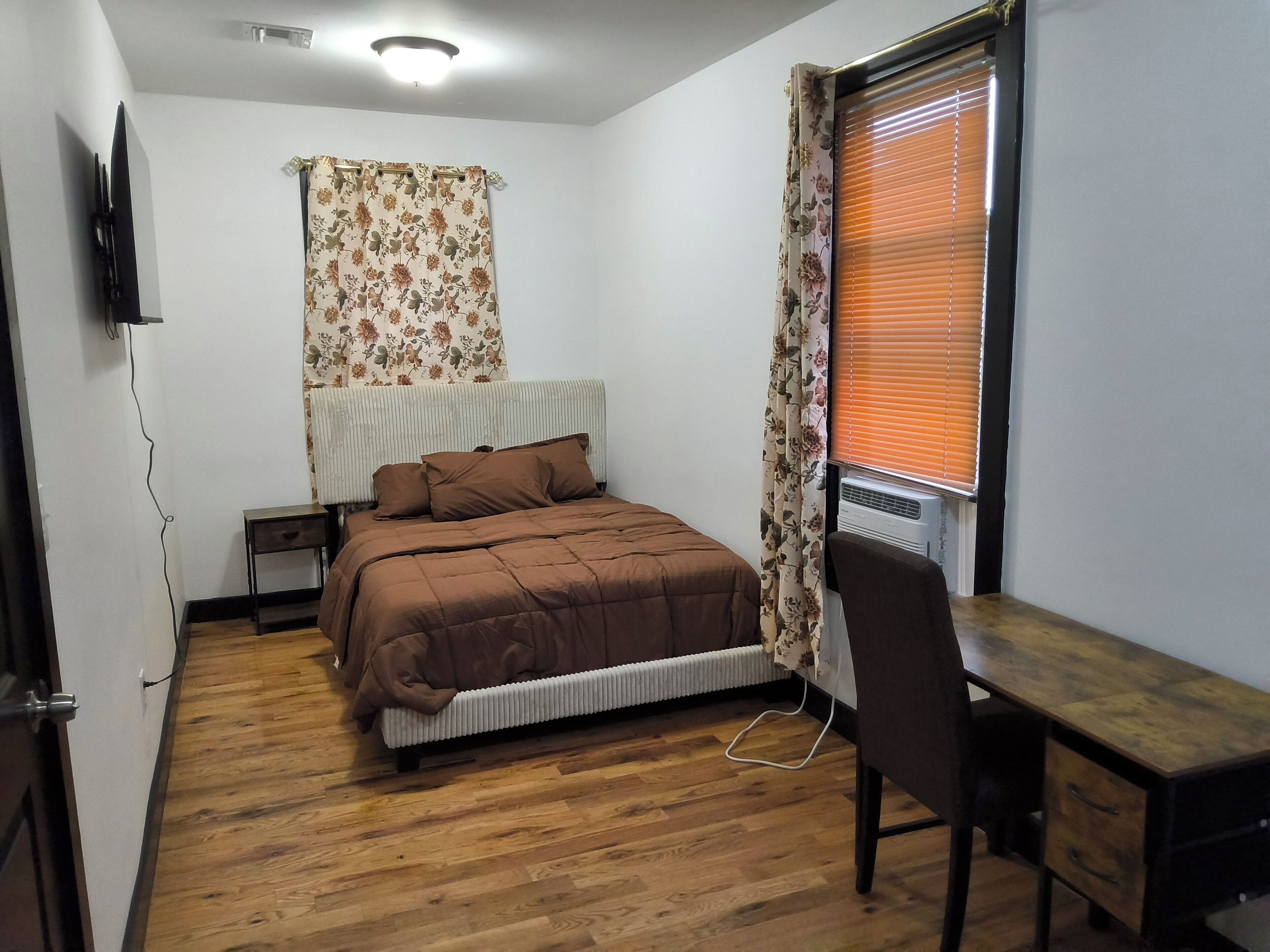 A bedroom with a bed, a desk, and a radiator.