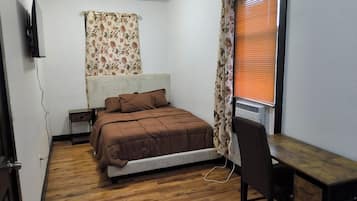 A bedroom with a bed, a desk, and a radiator.