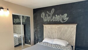 A bedroom with a bed, a headboard, a bedside table, and a wall with a 'Welcome' sign. - Relaxing Corner -Huge backyard - Hot Tub and Views (Tucson)