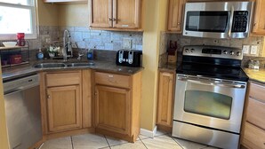 A kitchen with wooden cabinets, a stainless steel microwave, a stove, a dishwasher, and a sink. - Relaxing Corner -Huge backyard - Hot Tub and Views (Tucson)