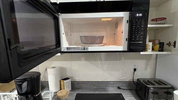 Eine Küche mit Mikrowelle, Toaster, Kaffeemaschine und einer Schüssel.
