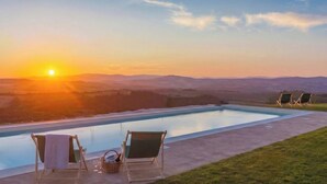 A pool with lounge chairs and a sunset view. - Private Hilltop Villa with Sea Views in the Heart of Maremma, Tuscany (Scansano)