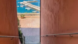 A stone staircase leading to a view of a coastal harbor with boats and a castle. - Private Hilltop Villa with Sea Views in the Heart of Maremma, Tuscany (Scansano)