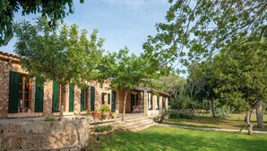 A stone building with green shutters, a covered porch, and a well-maintained lawn. - Sa Carrotja - Traditional villa with pool near the sea (Manacor)