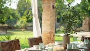An outdoor dining table with chairs, a vase with greenery, and glassware. - Sa Carrotja - Traditional villa with pool near the sea (Manacor)