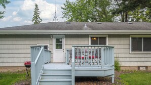 A house with a front porch, a set of stairs leading to the door, and a grill outside.
