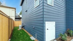 Un edificio residenziale con un'autorimessa, un piccolo giardino anteriore con erba e una recinzione in legno.