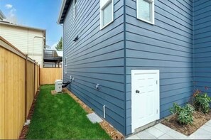 A residential building with a garage door, a small front yard with grass, and a wooden fence.