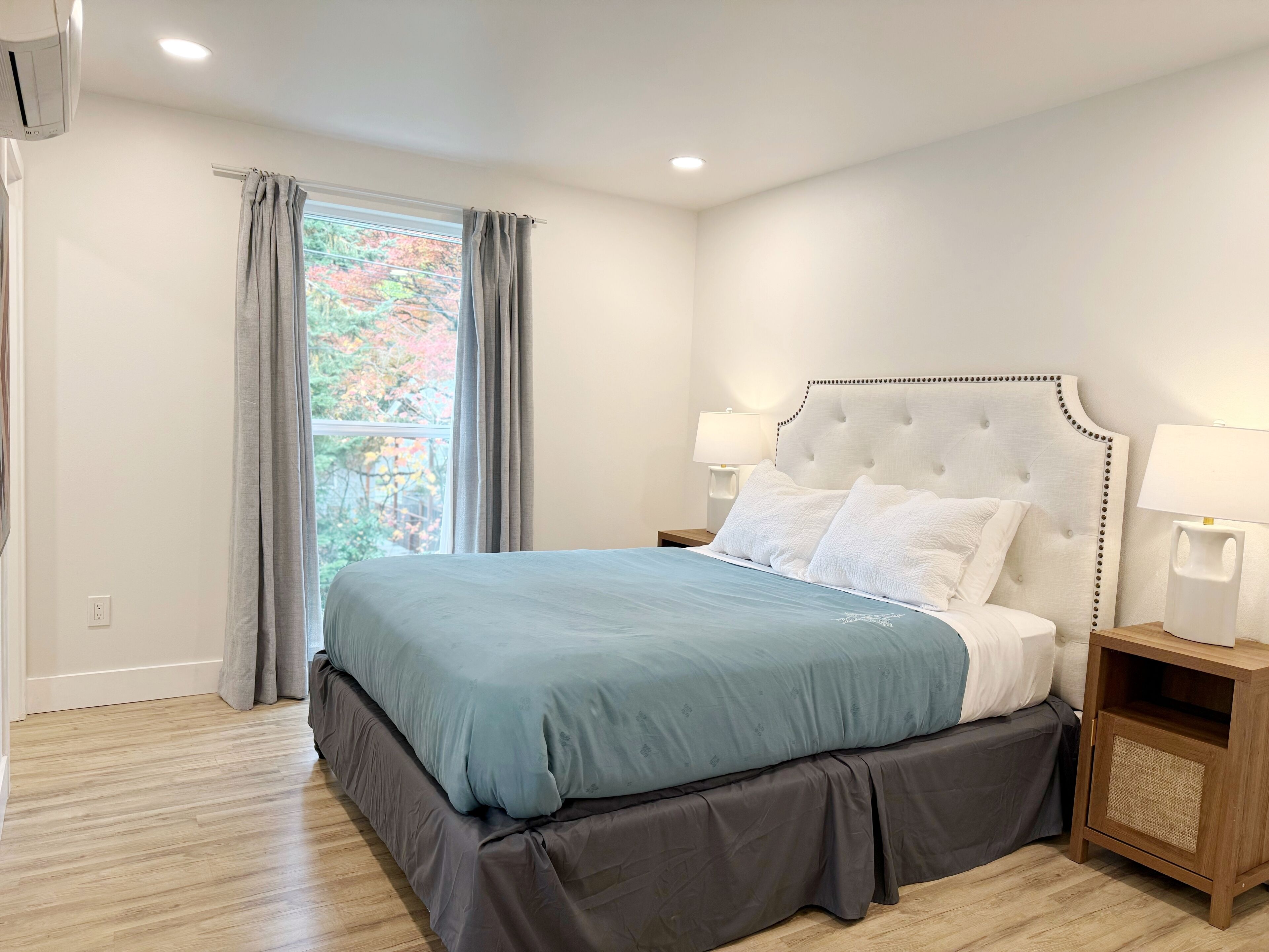 A bedroom with a bed, two bedside tables, and a window with curtains.