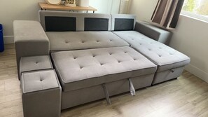 A sectional sofa with a chaise, a small table, and a window with curtains.