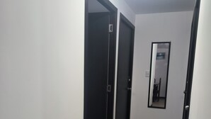 A hallway with wooden flooring, white walls, and black-framed doors.