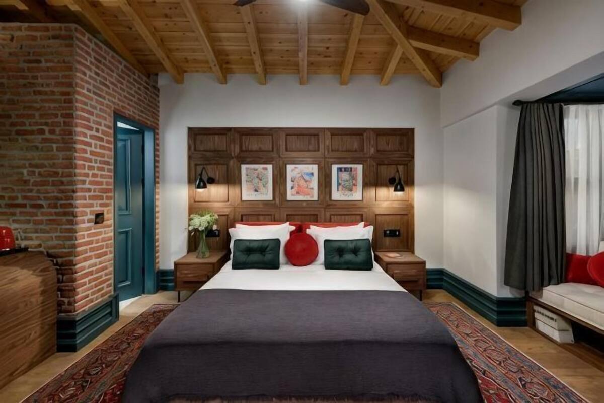 A bedroom with a large bed, wooden headboard, brick wall, and a ceiling fan.