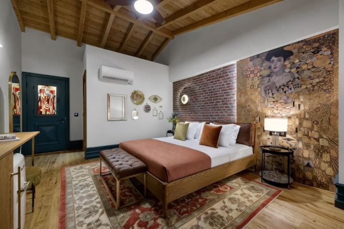 Une chambre à coucher comprenant un lit, un bureau, une chaise, une lampe et un mur décoratif.