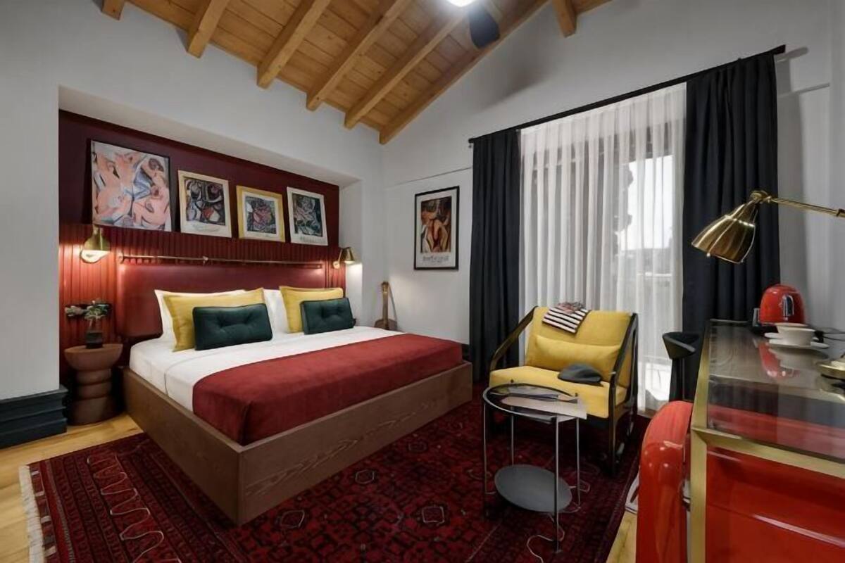 A bedroom with a bed, a desk, a chair, and a window with curtains.