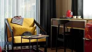 A room with a yellow armchair, a small round table, a red kettle, and a red cabinet. - Tinspiro Alaçatı (Cesme)