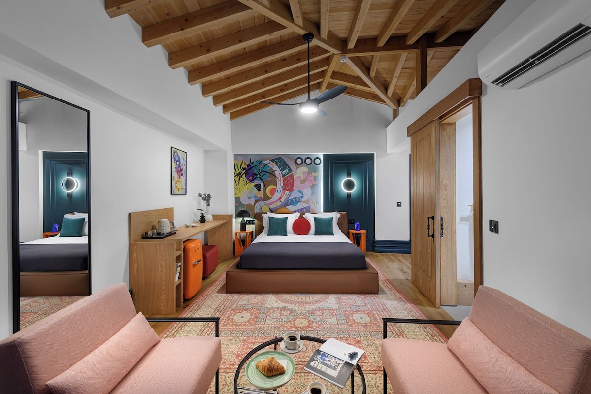 A modern bedroom with a large bed, a desk, a chair, and a coffee table.