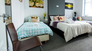 Ein Hotelzimmer mit zwei Betten, einem Sessel und Kunstwerken an den Wänden.