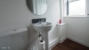 Ein Badezimmer mit weißem Waschbecken, Toilette, Spiegel und Fenster.