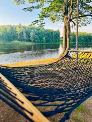 A hammock by a lake with a view of trees and a fence. - The Meadows - New! Menominee River Tiny Cottage (Porterfield)