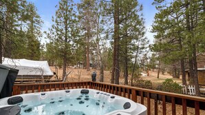 Un bain à remous sur une terrasse en bois, entouré d’une forêt.