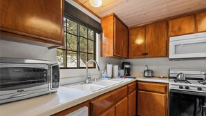 Une cuisine de taille réduite, dotée de meubles en bois, d’un four à micro-ondes, d’une cuisinière et d’un évier.