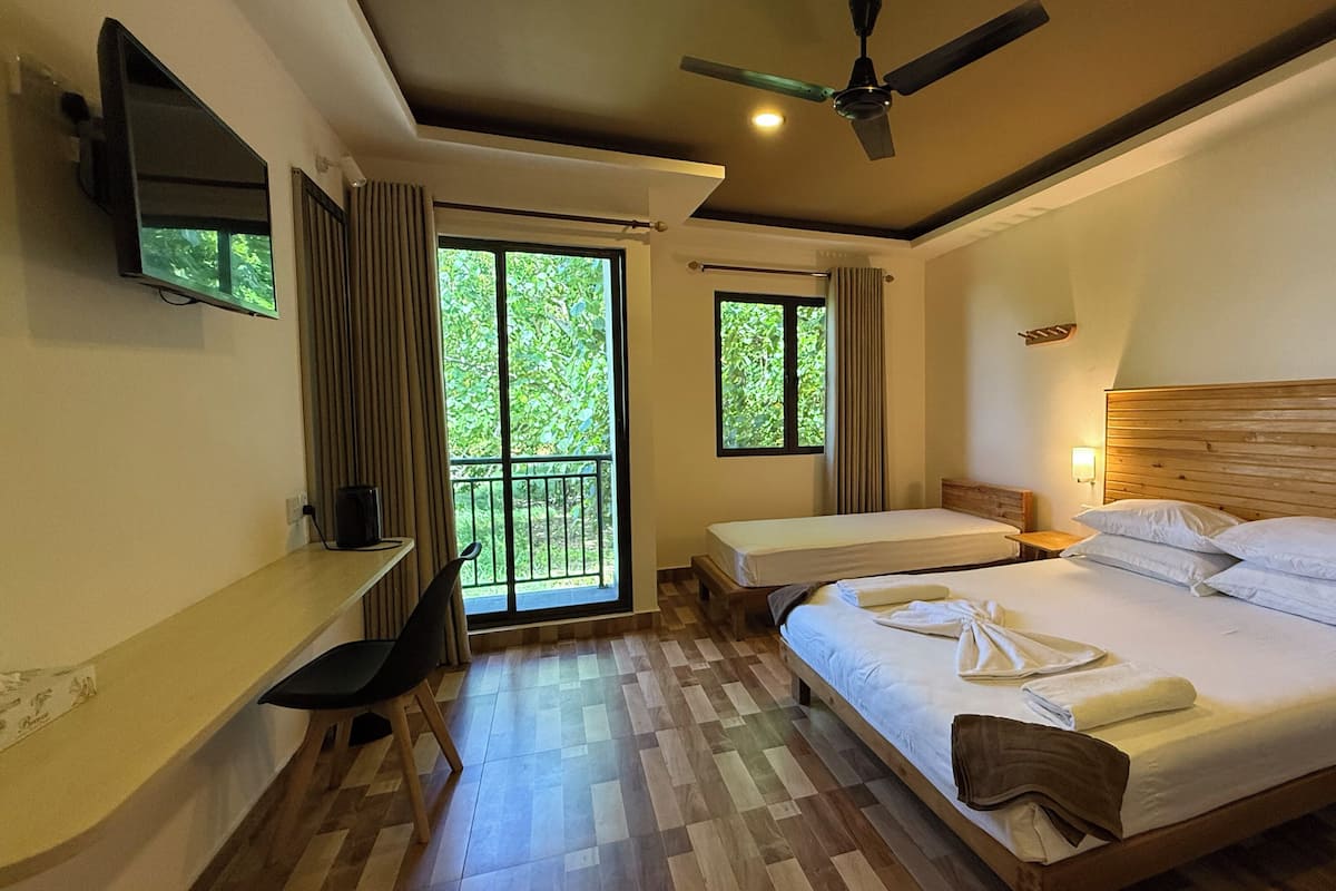 A hotel room with a large bed, two bedside tables, a TV mounted on the wall, and a ceiling fan.