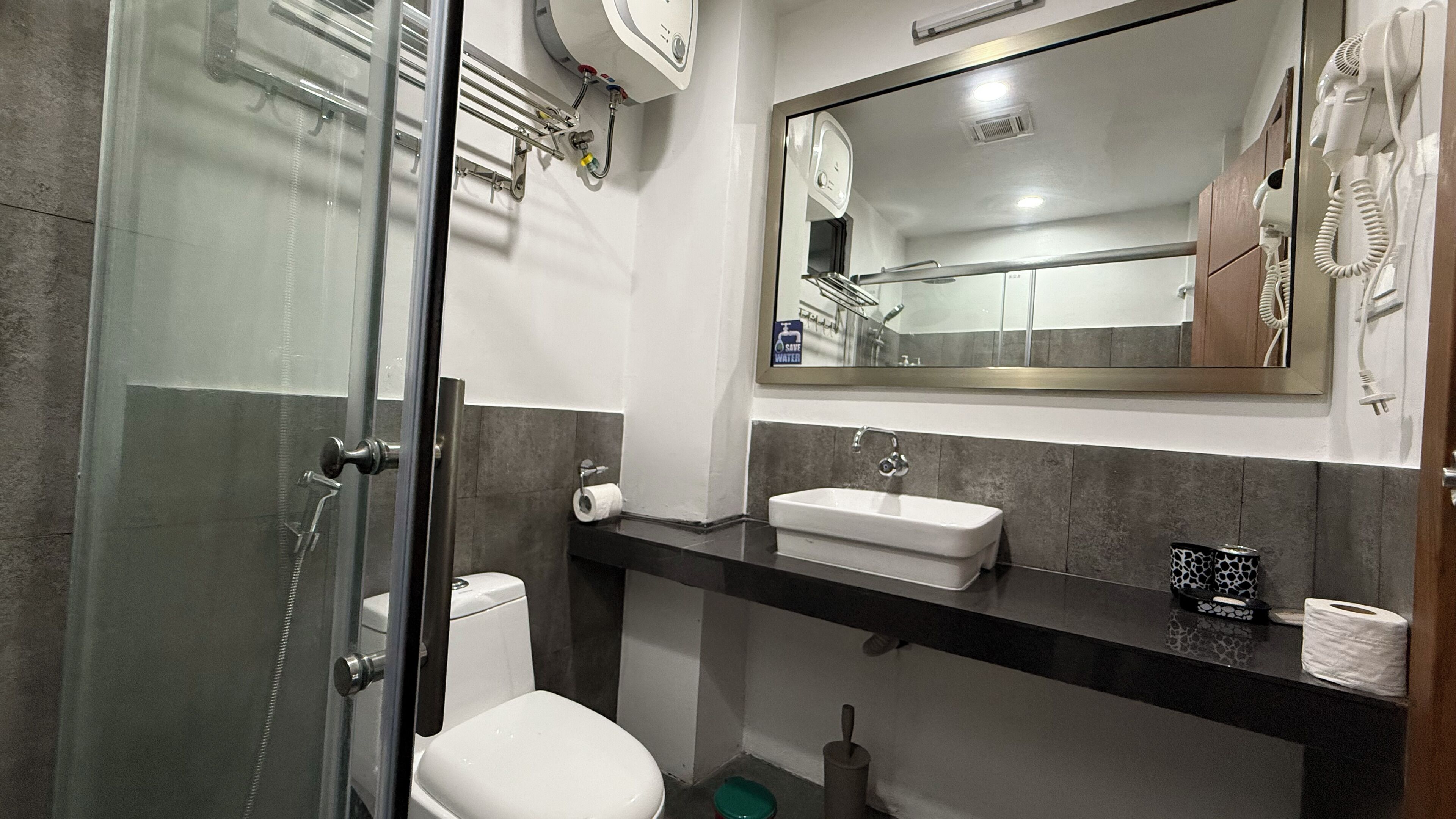 Ein Badezimmer mit Duschkabine aus Glas, einer weißen Toilette, einem Waschbecken mit Spiegel und einem Handtuchhalter.