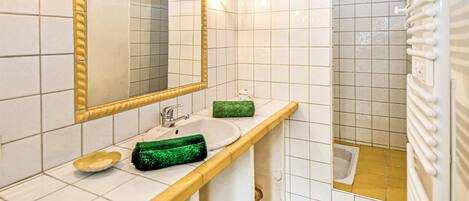 Un baño con lavamanos, espejo y ducha.