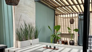 A modern outdoor seating area with a stone countertop, potted plants, and a wooden pergola. - Maya Heaven Penthouse in Tulum with Private Rooftop, Pool & Parking (Tulum)