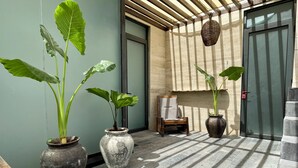 A modern indoor space with large potted plants, a wooden chair, and a hanging basket. - Maya Heaven Penthouse in Tulum with Private Rooftop, Pool & Parking (Tulum)