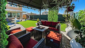 Un patio al aire libre con mobiliario de mimbre, una mesita y una planta en maceta.