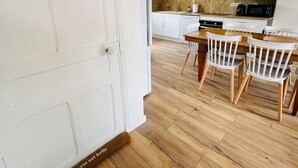 Una cocina moderna con armarios blancos, una mesa de comedor de madera y cuatro sillas blancas.