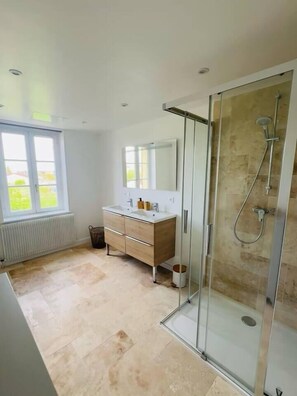 A modern bathroom with a glass shower enclosure, a double sink vanity, and a large mirror.
