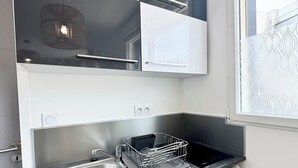 Eine kleine Küche mit Spüle aus Edelstahl, einem Geschirrgestell und einem Kühlschrank.