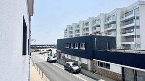 Straßenansicht mit einer Reihe geparkter Autos, einem Gebäude mit der Aufschrift "TEMPETE" und einem modernen Wohnkomplex im Hintergrund.