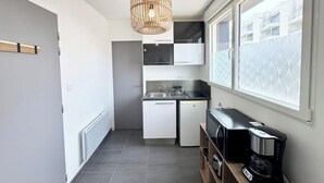 Eine kompakte Küche mit integriertem Geschirrspüler, Mikrowelle und Kaffeemaschine auf einer Holzwand.