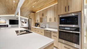 Una cocina moderna con armarios de madera, electrodomésticos de acero inoxidable y una isla central.