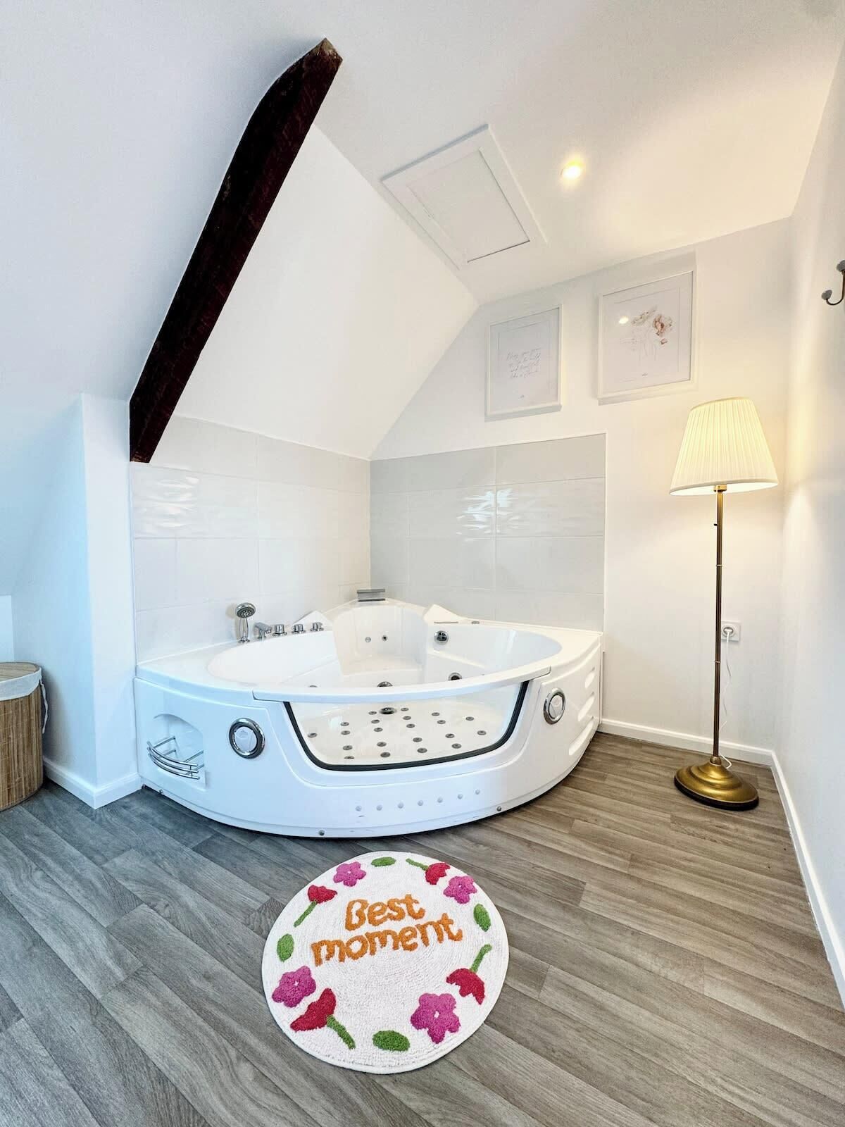 A modern bathroom with a freestanding bathtub, a round rug with 'Best moment' text, and a floor lamp.
