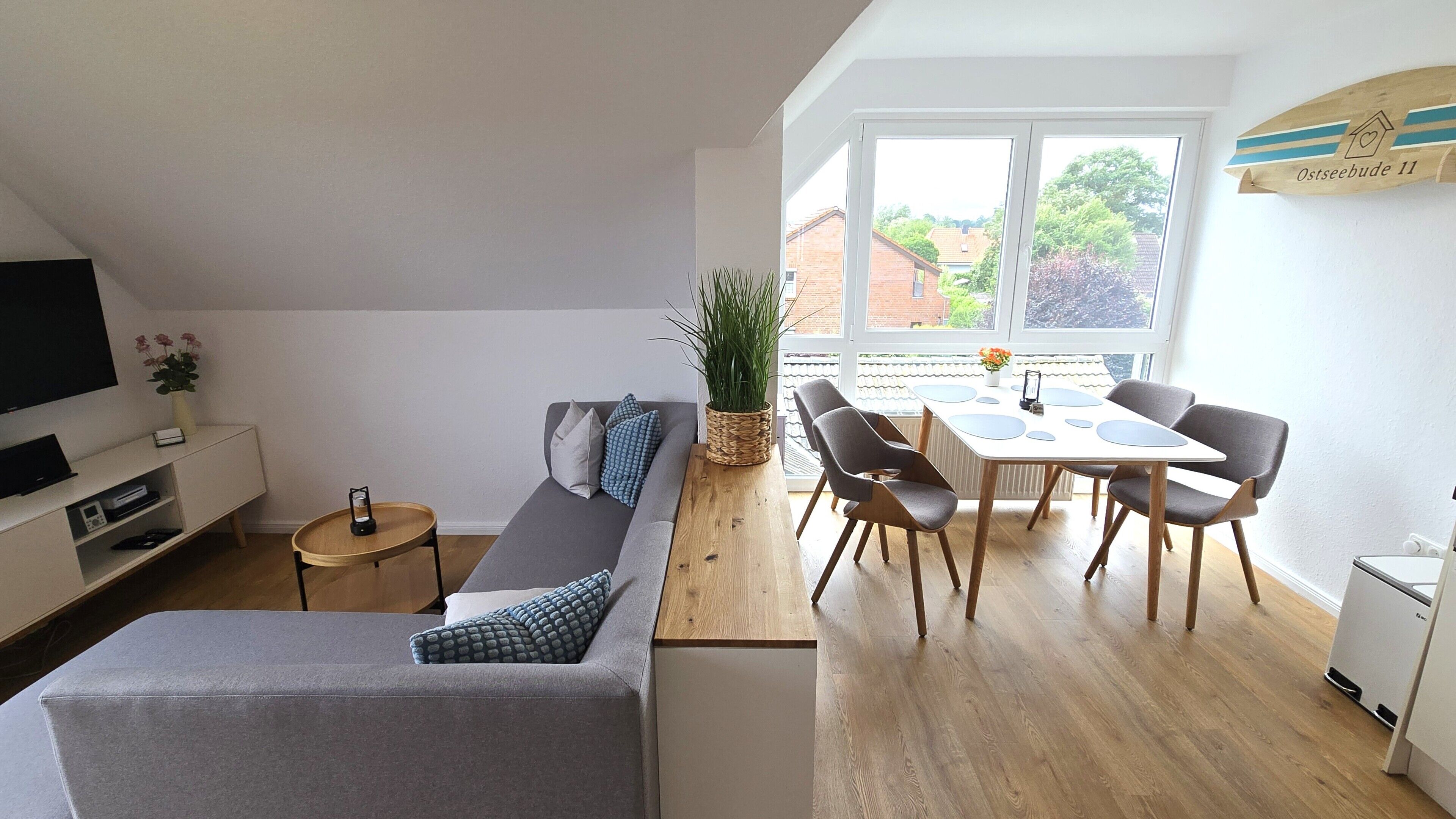 Un espacio habitable moderno con sofá, mesa de comedor, sillas, televisor y planta.